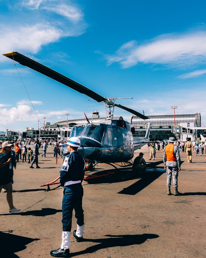 A military helicopter on display outdoors with a large crowd at an air show.